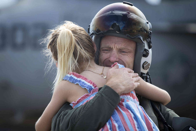 Commander Andrew “Sugar” Stoner reacts as he holds his daughter Katherine Stoner, 7, after returning to NAS Oceana in Virginia Beach, Va., on Friday, July 12, 2024. The pilots returned after a nearly nine-month deployment with the Dwight D. Eisenhower Carrier Strike Group. (Photo by Billy Schuerman/The Virginian-Pilot via AP Photo)