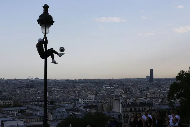 Iya Traore, a former professional football player, holds on to a lamppost as he performs for visitors in the Montmatre area of Paris, on June 9, 2014. (Photo by Ludovic Marin/AFP Photo)