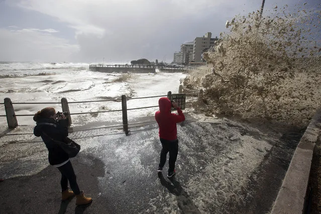 Huge waves slam into the promenade during heavy storms in the Sea Point neighborhood of Cape Town, South Africa, on Wednesday, June 7, 2017. South African media are reporting that several people have been killed in a storm that swept into the area around Cape Town. The region has been suffering a severe drought. News24 says four people were killed in a fire caused by lightning and another person died when a house collapsed. (Photo by Halden Krog/AP Photo)