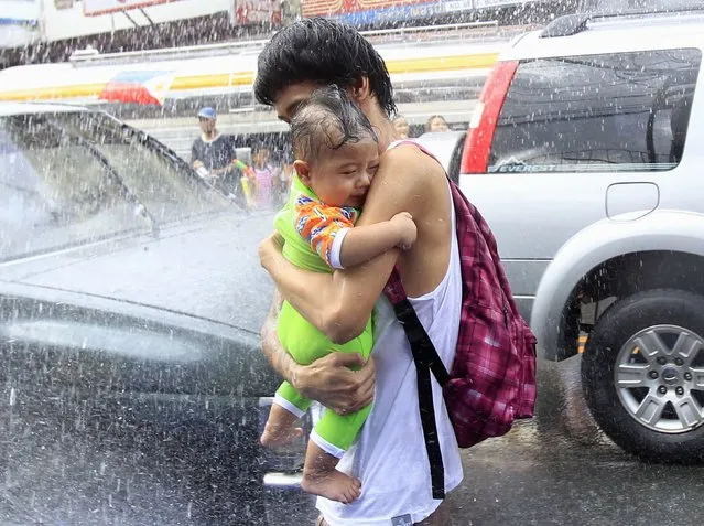 A man shields his baby from water being showered by firefighters and residents during St. John the Baptist Feast Day celebrations in San Juan city, metro Manila June 24, 2014. Residents participate in an annual city-wide waterfest in honour of their patron Saint John the Baptist. (Photo by Romeo Ranoco/Reuters)