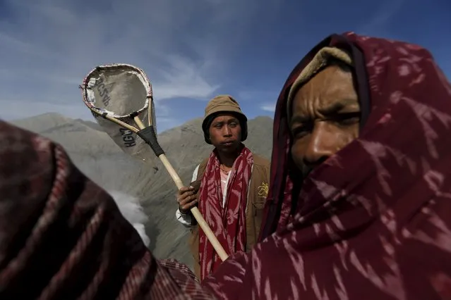 A man (C) holds a net as he waits with others to catch offerings thrown by Hindu worshippers during the Kasada Festival at the crater of Mount Bromo on August 1, 2015 in Probolinggo, Indonesia's East Java province. (Photo by Reuters/Beawiharta)