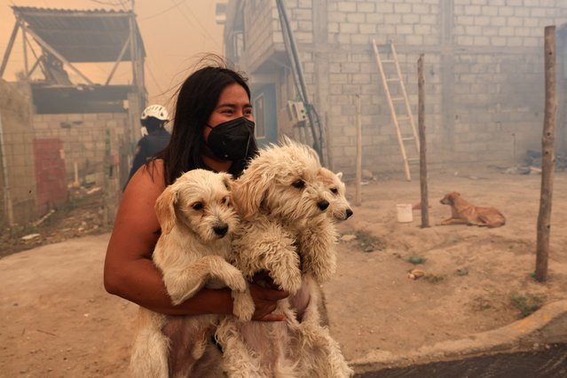 A woman carrying dogs looks on amid smoke from wildfires, in Tumbaco, Ecuador on September 5, 2024. (Photo by Karen Toro/Reuters)