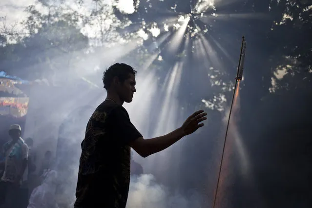 A man launches a fireworks rocket during the celebration of Managua's patron saint, Santo Domingo de Guzman, in Managua, Nicaragua, Saturday, August 1, 2015. The first 10 days of August are reserved for the carnival-like celebration of Santo Domingo with processions, bullfights, parties and church services. (Photo by Esteban Felix/AP Photo)
