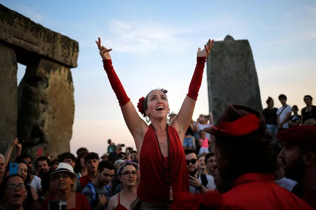 A singer leads hundreds of fellow revelers in song while waiting for the sun to set during the summer solstice festival at Stonehenge, Salisbury, Britain, 20 June 2017 (Issued 21 June 2017). The annual festival attracts hundreds of people to the 5000 year old stone circle to mark the longest day in the northern hemisphere. sunrise was at 4.52am and was celebrated by dancing, music, and ritualistic events around the stones. (Photo by Kim Ludbrook/EPA)