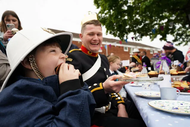 Will Hughes, 7, eats a cake whilst wearing the hat of band member Aaron Pitman on April 28, 2022. Residents of Church Hill in Redditch were surprised by members of the Royal Marines Band Service, who played a medley of tunes to recognise the community for stepping up to celebrate Queen Elizabeth's Platinum Jubilee this June, with over 40 Big Jubilee Lunches planned to bring neighbours together on local streets. (Photo by Jacob King/PA Wire)