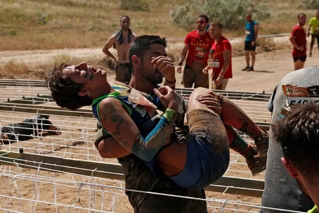 A participant is helped by an Spanish soldier at the electric shock area in the Mud Day Race extreme run competition at El Goloso military base, outside Madrid, Spain, June 11, 2016. (Photo by Juan Medina/Reuters)