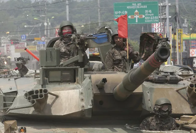 South Korean army soldiers ride a K-1 tank during the annual exercise in Paju, South Korea near the border with North Korea, Wednesday, July 5, 2017. Grinning broadly, North Korean leader Kim Jong Un delighted in the global furor created by his nation's first launch of an intercontinental ballistic missile, vowing Wednesday to never abandon nuclear weapons and to keep sending Washington more “gift packages” of missile and atomic tests. (Photo by Ahn Young-joon/AP Photo)