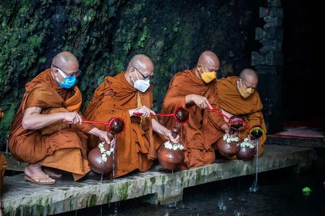 Buddhist monks collect holy water, used for blessing at Borobudur temple, during Vesak Day celebrations at Umbul Jumprit spring in Temanggung, Central Java on May 15, 2022. (Photo by Juni Kriswanto/AFP Photo)