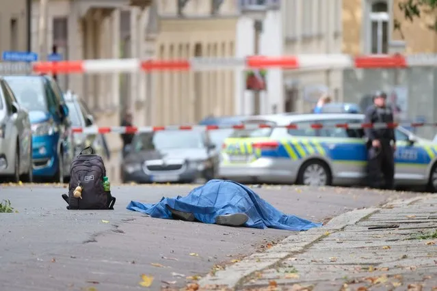 A body laying in the street is covered as police block the area around the site of a shooting in Halle an der Saale, eastern Germany, on October 9, 2019. At least two people were killed in a shooting on a street in the German city of Halle, police said, adding that the perpetrators were on the run. “Early indications show that two people were killed in Halle. Several shots were fired. The suspected perpetrators fled in a car”, said police on Twitter, urging residents in the area to stay indoors. (Photo by Sebastian Willnow/dpa/AFP Photo)