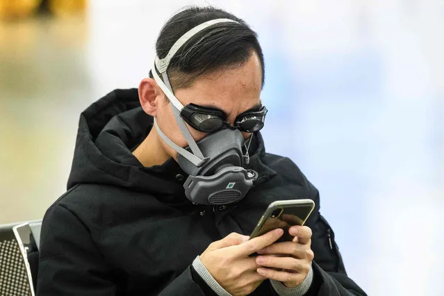 A passenger wears swimming goggles and a facemask as he waits inside the high-speed train station connecting Hong Kong to mainland China during a public holiday in celebration of the Lunar New Year in Hong Kong on January 28, 2020, as a preventative measure following a virus outbreak which began in the Chinese city of Wuhan. China on January 28 urged its citizens to postpone travel abroad as it expanded unprecedented efforts to contain a viral outbreak that has killed 106 people and left other governments racing to pull their nationals from the contagion's epicentre. (Photo by Anthony Wallace/AFP Photo)