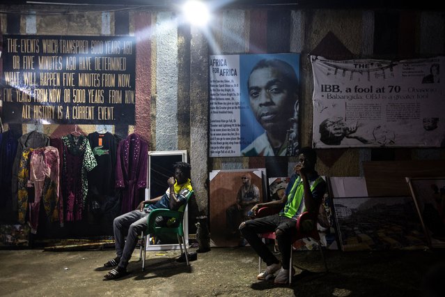 Men sits next to a poster of Fela Kuti, a Nigerian musician and political activist who is regarded as the principal innovator of Afrobeat, at the entrance of the New Afrika Shrine during the Felabration week in the district of Ikeja in Lagos on October 14, 2024. Every year Lagos celebrates the musical legacy of Fela Kuti with a week of concerts at the legendary New Afrika Shrine in the working-class district of Ikeja. (Photo by Olympia de Maismont/AFP Photo)