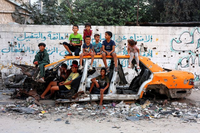 Palestinian children gather at a destroyed vehicle, amid the Israel-Hamas conflict, in Khan Younis in the southern Gaza Strip, on September 30, 2024. (Photo by Mohammed Salem/Reuters)