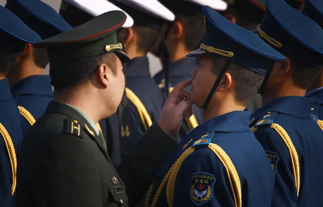 A Chinese officer touches underneath the nose of a member of an honor guard at Beijing airport. (Photo by David Gray/Reuters)