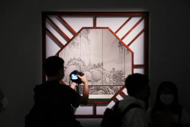 A man holds a camera in front of an exhibit displayed during a media preview at the Palace Museum in Hong Kong, China on June 22, 2022. (Photo by Lam Yik/Reuters)