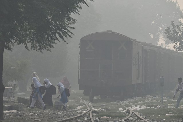 School girls walk across a railway track amid heavy smog in Lahore on October 29, 2024. (Photo by Arif Ali/AFP Photo)