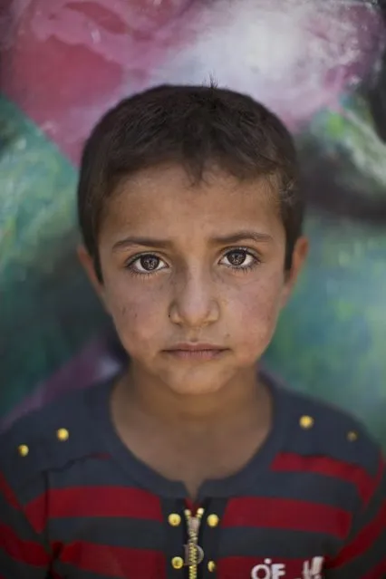 In this Tuesday, July 29, 2014, photo, Syrian refugee Kamel, 7, poses for a picture at Zaatari refugee camp, just over the border with Syria in Mafraq, Jordan. The horror of that country's civil war can be seen in the faces of its youngest refugees. (Photo by Muhammed Muheisen/AP Photo)