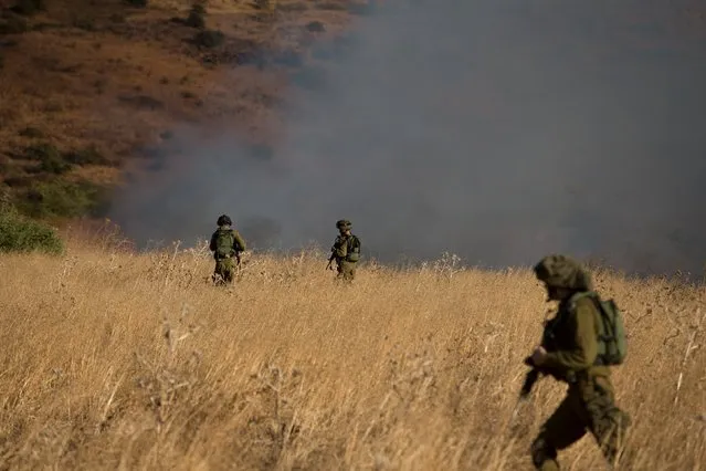 Israeli soldiers patrol next to a smoke from a fire caused by a rocket attack in northern Israel, near the Lebanese border, August 20, 2015. Rockets that struck a northern Israeli village near the Lebanese border on Thursday, causing no casualties, were launched from the Syrian Golan Heights, the Israeli army said. (Photo by Reuters/Stringer)