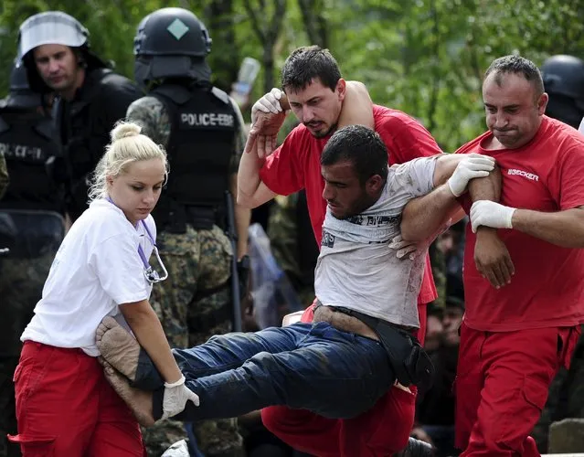 Red Cross workers assist a collapsed migrant after he crossed Greece's border with Macedonia, in Gevgelija, Macedonia, August 22, 2015. (Photo by Ognen Teofilovski/Reuters)