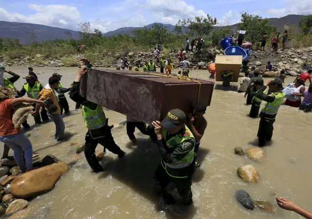 Colombian policemen carry items belonging to people arriving in Colombia while crossing the Tachira river border with Venezuela, near Villa del Rosario village August 25, 2015. (Photo by Jose Miguel Gomez/Reuters)