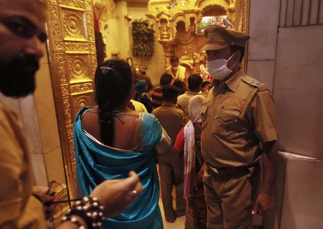 A security officer wearing a protective mask stands guard inside a temple in Mumbai, India on March 13, 2020. (Photo by Francis Mascarenhas/Reuters)