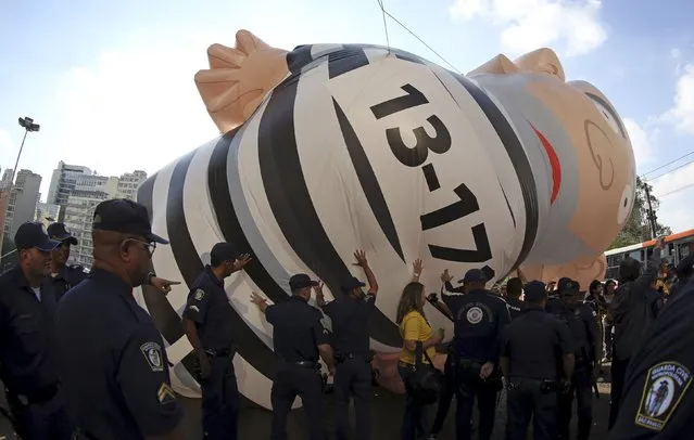 Members of the Metropolitan Police remove a giant inflatable doll that depicts former Brazilian President Luiz Inacio Lula da Silva in prison attire during a protest against Brazil's President Dilma Rousseff and the Workers' Party in downtown Sao Paulo, Brazil, August 28, 2015. (Photo by Paulo Whitaker/Reuters)