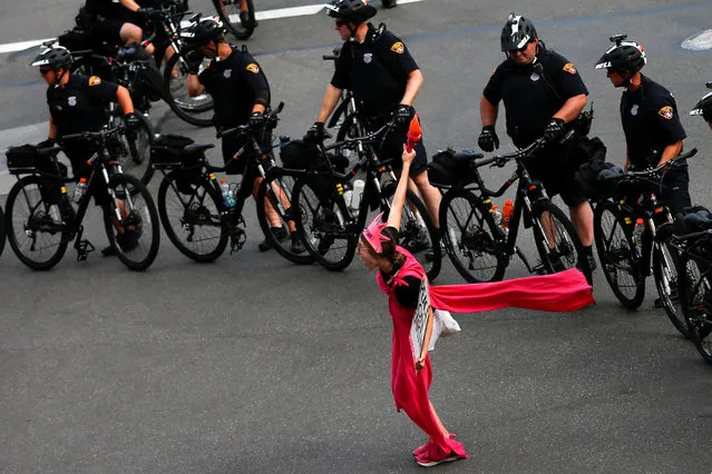 An activist with Code Pink poses next to police on bicycles monitoring a protest march by various groups, including “Black Lives Matter” and "Shut Down Trump and the RNC" ahead of the Republican National Convention in Cleveland, Ohio, U.S., July 17, 2016. (Photo by Adrees Latif/Reuters)