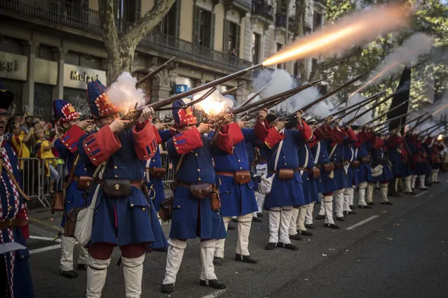 Men wearing reproductions of Catalan military costumes of the 18th century shoot blaze weapons during a performance during the Catalan National Day in Barcelona, Spain, on Monday, September 11, 2017. Hundred of thousands of people are expected to demonstrate in Barcelona to call for the creation of a new Mediterranean nation, as they celebrate the Catalan National Day holiday. (Photo by Santi Palacios/AP Photo)