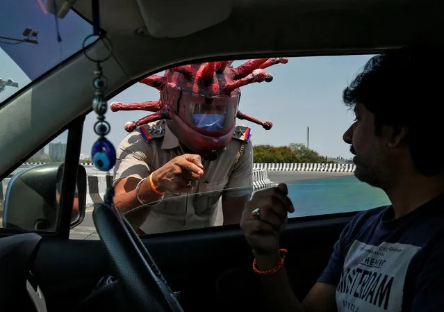 Rajesh Babu, a police officer, wearing a helmet depicting coronavirus, requests a commuter to stay at home during a 21-day nationwide lockdown to limit the spreading of coronavirus disease (COVID-19), in Chennai, India, March 28, 2020. (Photo by P. Ravikumar/Reuters)