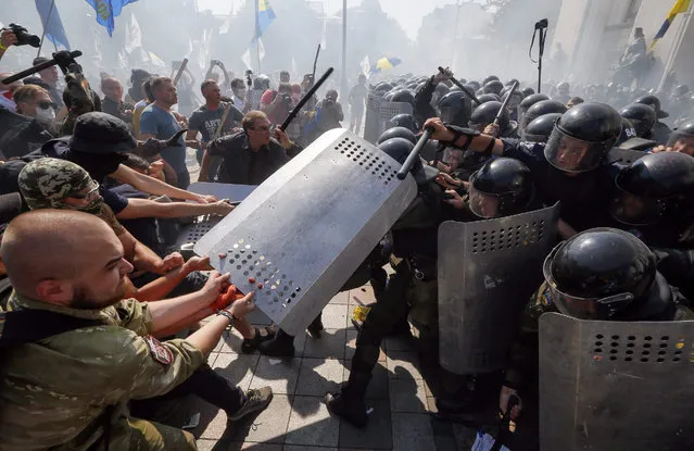 Opponents of changes to Ukrainian Constitution clash with police in front of Ukrainian Parliament in Kiev, Ukraine, 31 August 2015 as lawmakers accepted the project to changing Ukrainian Constitution about decentralization of power in first reading. A grenade exploded outside Ukraine's parliament 31 August during a protest as legislators voted in favour of a draft law to give special status to the eastern regions that are locked in a conflict between the Ukrainian military and pro-Russian separatists. (Photo by Sergey Dolzhenko/EPA)