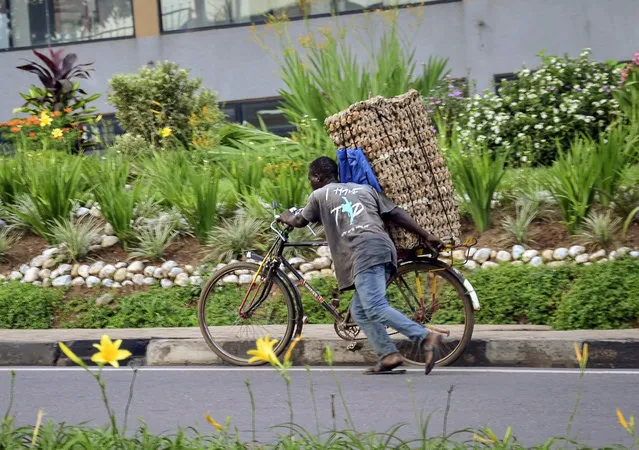 In this photo taken Thursday, March 26, 2020 a man transports cartons of eggs on the back of a bicycle due to restrictions on movement attempting to halt the spread of the new coronavirus, in Kigali, Rwanda. (Photo by AP Photo/Stringer)