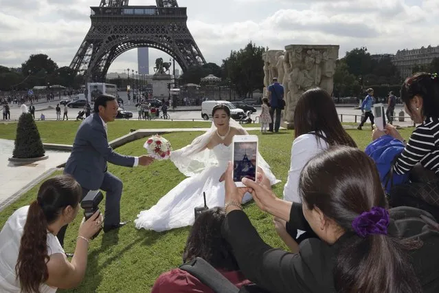 A Chinese couple poses during a pre-wedding photoshoot in front of the Eiffel tower, in Paris, France, August 28, 2015. (Photo by Philippe Wojazer/Reuters)