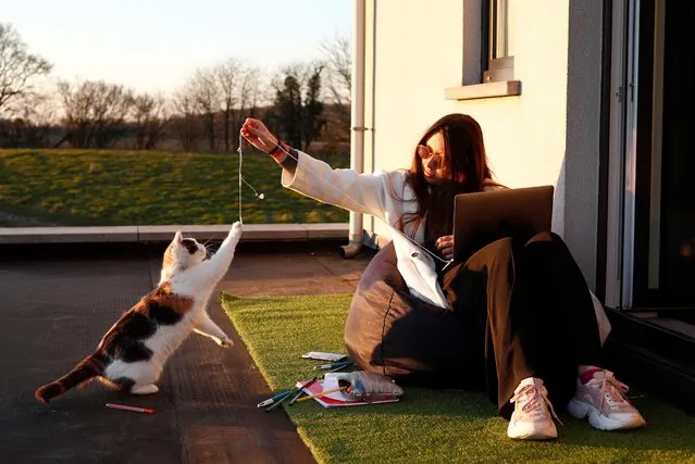 Lea, 19, plays with her cat as she studies in her house, during the lockdown imposed by the Belgian government to slow down the coronavirus disease (COVID-19) spread, in Moorsel, Belgium March 31, 2020. (Photo by Francois Lenoir/Reuters)