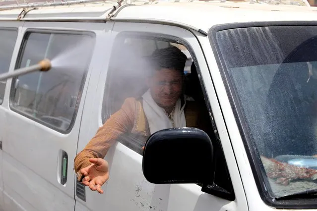 A health worker sprays disinfectant on a man in a van while the spread of the coronavirus disease (COVID-19) continues, on the outskirts of Sanaa, Yemen on April 13, 2020. (Photo by Khaled Abdullah/Reuters)
