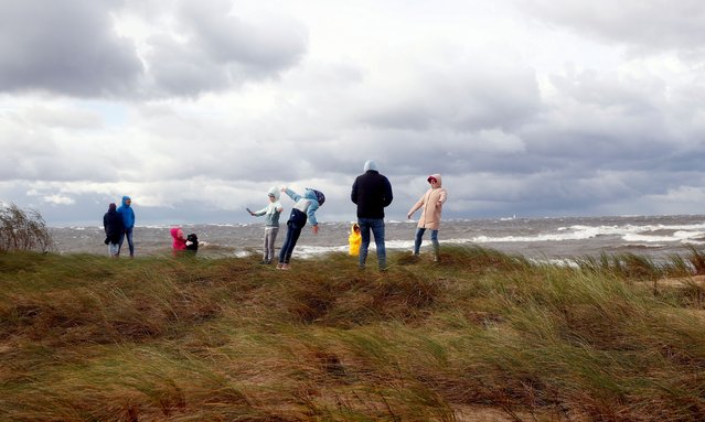 People enjoy a walk during stormy weather at Mangalsala beach in Riga neighborhood, Latvia, 08 October 2023. High, gusty winds persist in Latvia on 08 October, though they have abated slightly compared to the storm the previous days. Nevertheless, a yellow warning for high winds remains in place across the country and is upgraded to an orange warning along the coast. (Photo by Toms Kalnins/EPA/EFE)