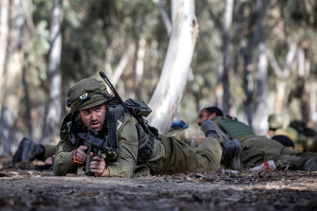 Israeli soldiers take cover after a warning of potential incoming fire from Gaza at the site of the surprise attack launched by Hamas on October 7th during a dance party near Reim, Israel on November 6, 2023. (Photo by Evelyn Hockstein/Reuters)