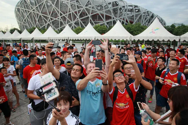 Fans take selfies as they gather near the National Stadium, also known as the Bird's Nest stadium, after the match between Manchester United and Manchester City was called off in Beijing, China, July 25, 2016. (Photo by Reuters/Stringer)