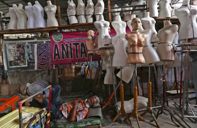 In this Thursday, April 30, 2020, photo, a man naps among mannequins at Tanah Abang textile market that is closed due to the new coronavirus outbreak in Jakarta, Indonesia. May Day usually brings both protest rallies and celebrations rallies marking international Labor Day. This year it's a bitter reminder of how much has been lost for the millions left idle or thrown out of work due to the coronavirus pandemic. Garment workers in Asia are among the hardest hit as orders dry up and shutdowns leave factories shuttered. (Photo by Tatan Syuflana/AP Photo)