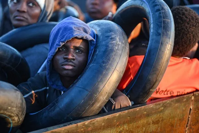Migrants from sub-Saharan Africa sit in a makeshift boat that was being used to clandestinely make its way towards the Italian coast, as they are found by Tunisian authorities about 50 nautical miles in the Mediterranean sea off the coast of Tunisia's central city of Sfax on October 4, 2022. (Photo by Fethi Belaid/AFP Photo)