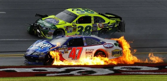 Flames engulf Bobby Labonte's car after the wreck as David Gilliland passes him at Talladega Superspeedway, on October 7, 2012. Daytona 500 winner Matt Kenseth avoided the wreckage and won under caution. (Photo by Rainier Ehrhardt/Associated Press)