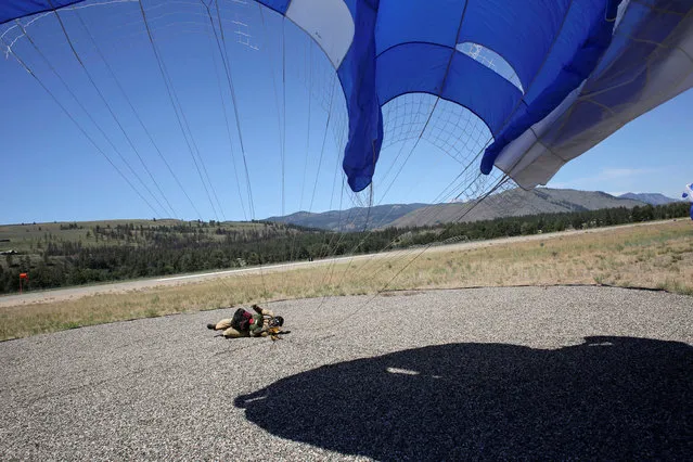 A smokejumper lands in a large gravel circle after leaping from an airplane during a training exercise at the North Cascades Smokejumper Base in Winthrop, Washington, U.S., June 6, 2016. On a 100-degree day in early June,  eight experienced firefighters did sit-ups in a semicircle  training to parachute into a wildfire. Better known as “rookie candidates”, they were determined to make it through the five-week program at North Cascades Smokejumper Base in Winthrop, Washington, where the first experimental jumps occurred in 1939. (Photo by David Ryder/Reuters)