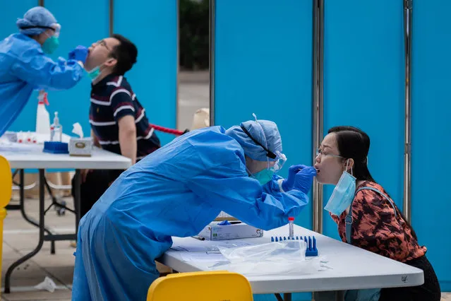 Medical workers wearing full protective gear take swab samples from a journalist to test for the COVID-19 coronavirus, nine hours before the closing ceremony of the National People's Congress (NPC) at the Diaoyutai hotel in Beijing on May 28, 2020. All journalists accredited to cover the National People's Congress events have to pass the COVID-19 test. (Photo by Nicolas Asfouri/AFP Photo)