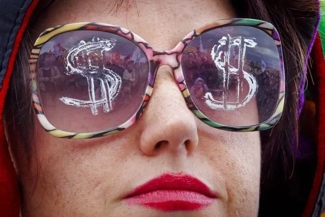 People gathered for a protest rally are reflected in glasses of a participant, in downtown St.Petersburg, Russia, Sunday, September 13, 2015. About 300 people have held a protest in Russia's second-largest city over the destruction of a century-old bas-relief of the demon Mephistopheles, and called for greater protection of other historical buildings and parks they say are under threat. (Photo by Dmitry Lovetsky/AP Photo)