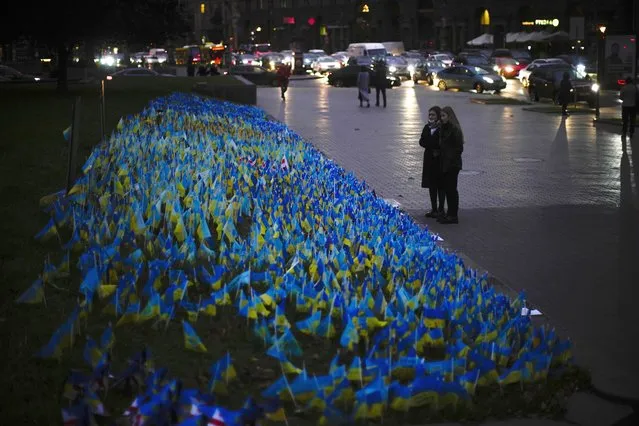 Two woman stand next to Ukrainian flags placed in memory of civilians killed during the war at the Independence square in central Kyiv, Thursday, October 20, 2022. (Photo by Francisco Seco/AP Photo)
