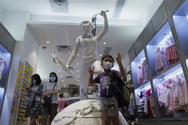 A boy poses in front of a statue named “Lady Liberty Hong Kong”, which was inspired by the outfits of anti-extradition law protesters at a local retail children's wear store, Chickeeduck, in Hong Kong, Thursday, June 18, 2020. A shopping center management company ordered Chow to remove a protest statue from its store saying it was inconsistent with the lease agreement. (Photo by Kin Cheung/AP Photo)