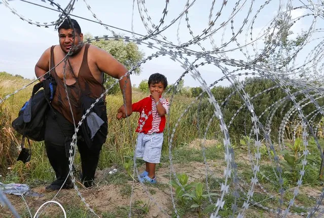 A migrant and a child walk along the fence on the Serbian side of the border with Hungary in Asotthalom, September 15, 2015. (Photo by Laszlo Balogh/Reuters)