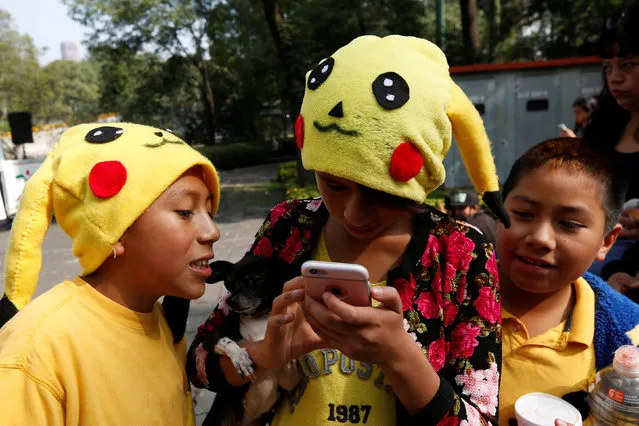 Children wearing hats of a Pokemon character, Pikachu, play Pokemon Go during a gathering to celebrate “Pokemon Day” in Mexico City, Mexico August 21, 2016. (Photo by Carlos Jasso/Reuters)