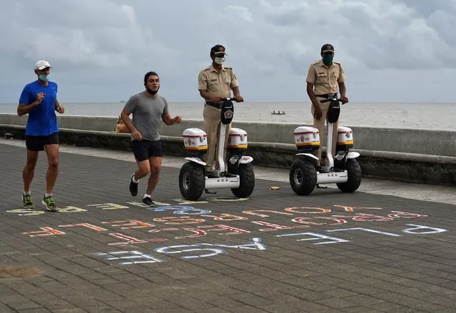 Police officers patrol on Segways as men wearing protective face masks run along the promenade at Marine Drive, after authorities eased lockdown restrictions that were imposed to slow the spread of the coronavirus disease (COVID-19), in Mumbai, India, June 12, 2020. (Photo by Hemanshi Kamani/Reuters)
