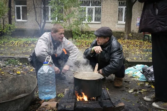 Local residents cook outdoor near their house in Bakhmut, the site of the heaviest battle against the Russian troops in the Donetsk region, Ukraine, Wednesday, October 26, 2022. (Photo by Efrem Lukatsky/AP Photo)