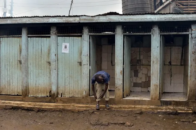 A man rolls up his trousers before using a public toilet on November 8, 2017 in the Kibera slum of Nairobi, Kenya. (Photo by Simon Maina/AFP Photo)