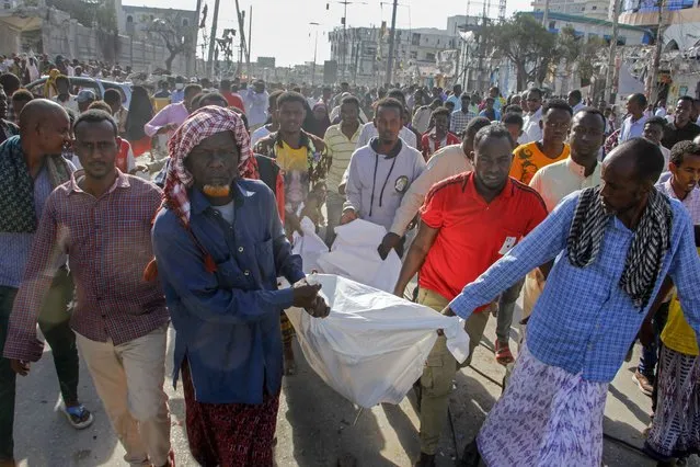 Relatives remove a body from the scene, a day after a double car bomb attack at a busy junction in Mogadishu, Somalia Sunday, October 30, 2022. (Photo by Farah Abdi Warsameh/AP Photo)